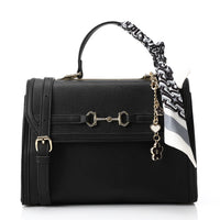 Black handbag with gold accents and a zebra-striped strap on a white background