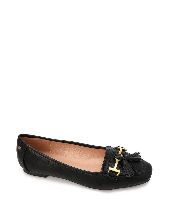 A single black leather flat shoe with a gold-tone decorative buckle and a black tassel detail on the toe, shown against a plain white background.